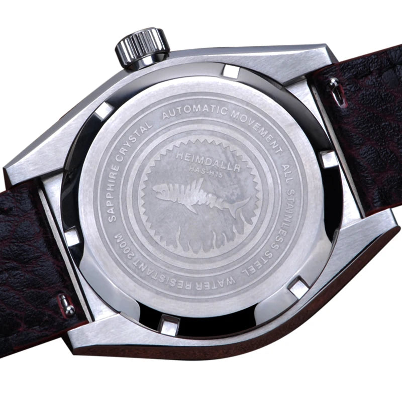 NorthChrono watch caseback featuring a robust stainless steel design with engraved brand name "HEIMDALLR," indicating "Automatic Movement," "All Stainless Steel," and "Sapphire Crystal." Accompanied by a dark leather strap, emphasizing durability.