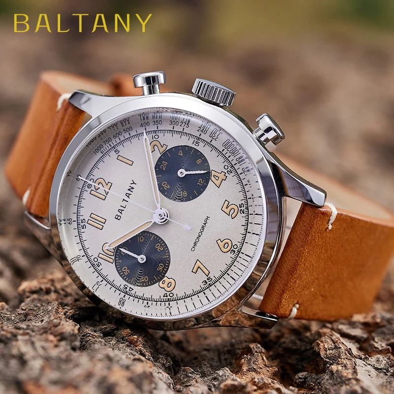 NorthChrono stylish chronograph watch featuring a silver-tone case, light-colored dial with dark sub-dials, and a brown leather strap. The brand "BALTANY" is visible on the dial, set against a textured wood background.