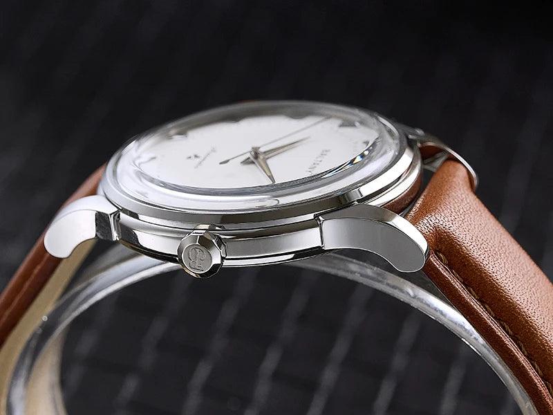 NorthChrono close-up of a minimalist round silver case watch featuring a white dial with light-colored hands and a brown leather strap, set against a dark textured background.