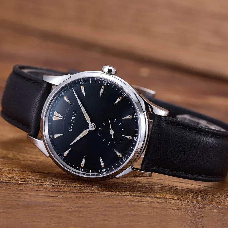 NorthChrono elegant dress watch featuring a black dial with silver hour markers and hands, a sub-dial for timekeeping functions, and a silver-tone case with a black leather strap, positioned on a rustic wooden surface.