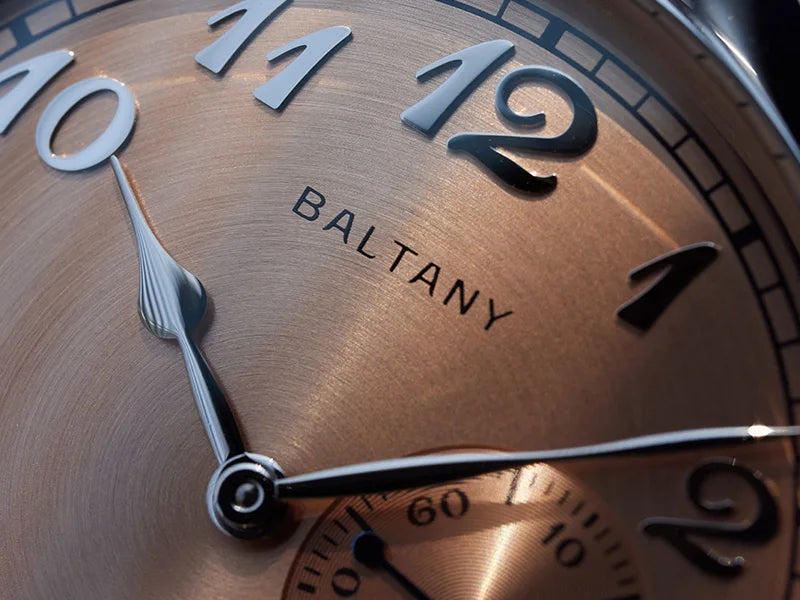 NorthChrono close-up of a BALTANY watch featuring a bronze-colored dial with silver hour markers, including 10, 11, and 12, and stylish silver hands, set against a dark background.