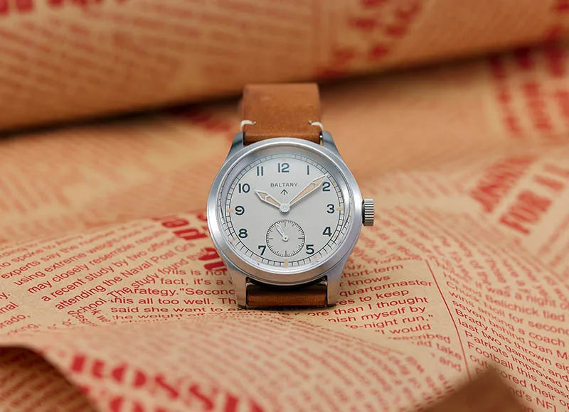 NorthChrono silver-tone watch with a white dial featuring black Arabic numerals and a small sub-dial, complemented by a brown leather strap, resting on a textured paper background with printed text, creating a vintage aesthetic.