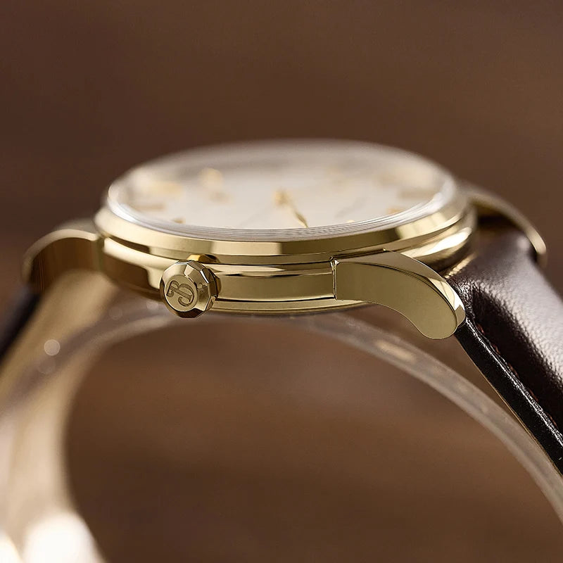 NorthChrono close-up of a gold-tone watch featuring a white dial with gold hour markers and side crown, complemented by a brown leather strap, set against a blurred wood surface background, highlighting its elegant design.