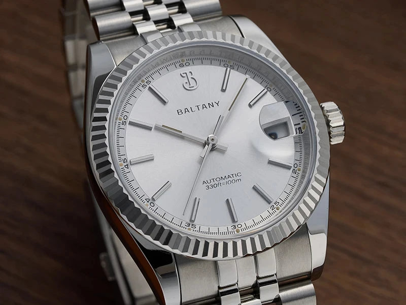 NorthChrono silver automatic watch with a round white dial, featuring the brand name "BALTANY," hour markers, luminous hands, and a date window at the 3 o'clock position, complemented by a stainless steel bracelet.