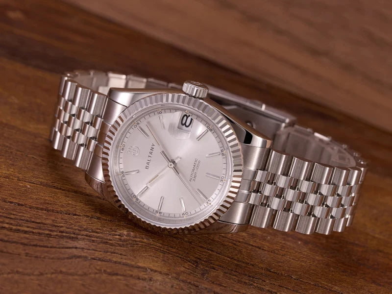 NorthChrono stainless steel watch with a silver dial, displaying a date function at the 3 o'clock position, paired with a metal bracelet, resting on a wooden surface to accentuate its design and craftsmanship.