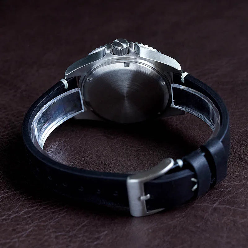 NorthChrono stainless steel automatic watch caseback with a prominent crown, featuring a black leather strap with a metallic buckle, set against a textured brown surface.