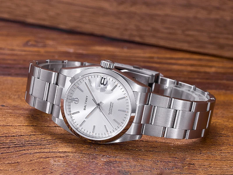 NorthChrono silver wristwatch with a stainless steel band, featuring a white dial with minimalistic hour markers and a date display at 3 o'clock, resting on a wooden surface. Classic and refined design.