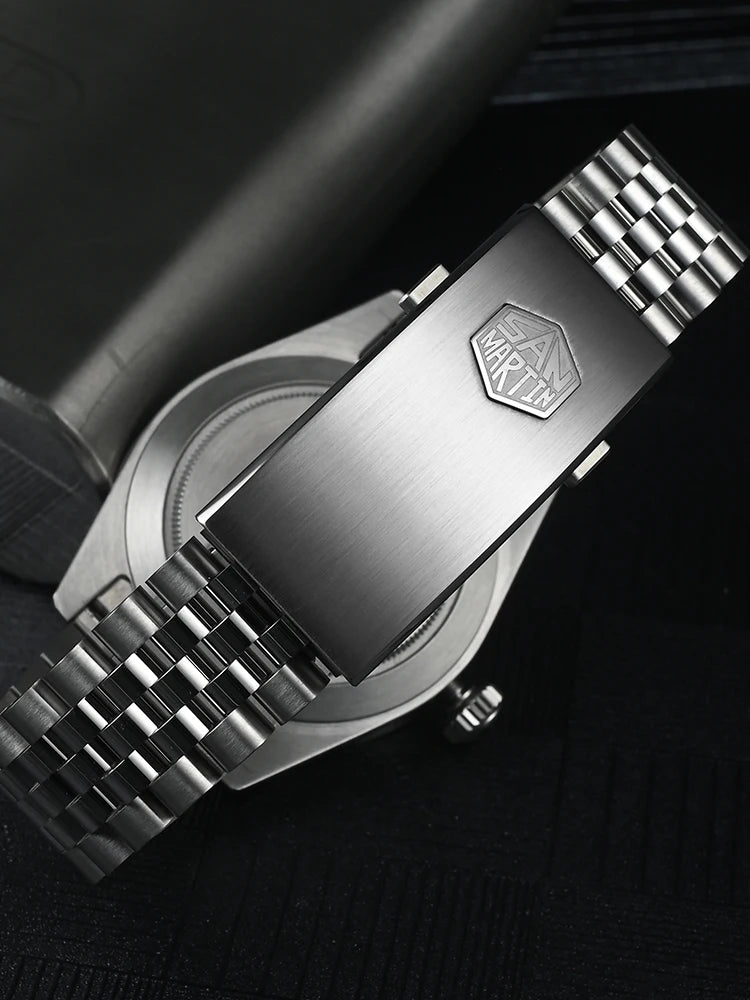 NorthChrono close-up of a metallic watch with a brushed stainless steel bracelet and engraved clasp. The dark textured background highlights the watch's luxury and style.