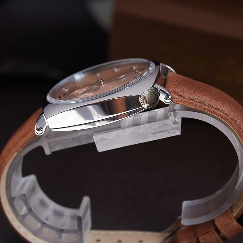 NorthChrono close-up of a metallic case watch with a polished finish, featuring a light-colored textured dial with hour markers and hands, complemented by a brown leather strap, set on a display stand.