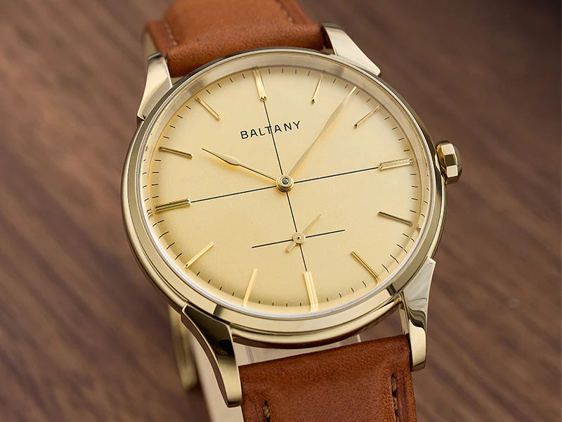 NorthChrono gold-colored watch with a beige dial featuring slender hour markers and hands, branded "BALTANY," complemented by a brown leather strap, placed on a wooden surface.