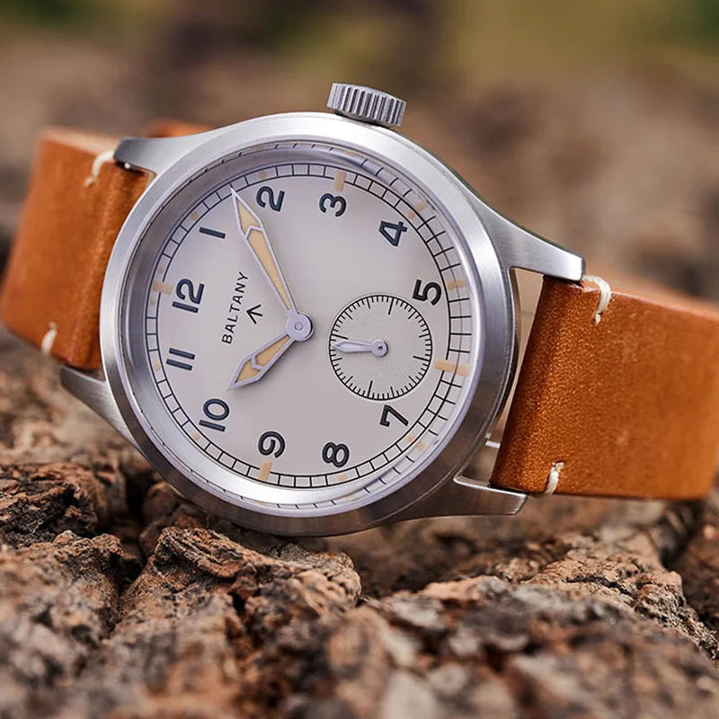 NorthChrono silver stainless steel wristwatch with a brown leather strap, featuring a minimalist white dial with black hour markers, silver hands, and a small seconds sub-dial, set against a natural wood background.