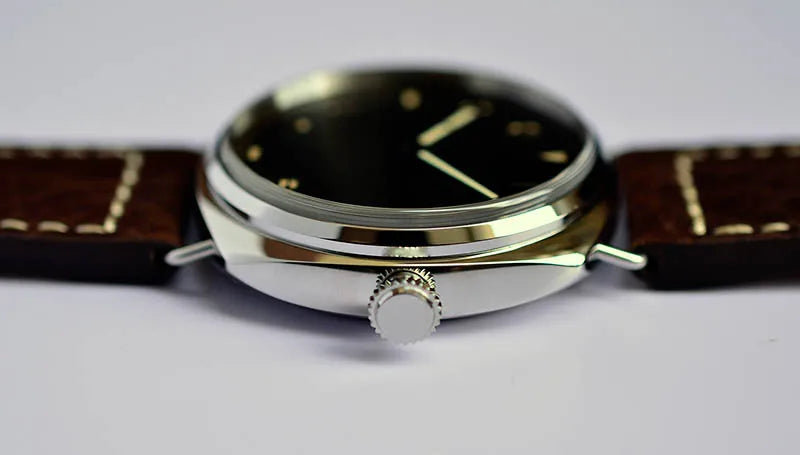 NorthChrono close-up of a round silver case wristwatch featuring a black dial with gold markers, a side crown, and a brown leather strap with visible stitching. Suitable for casual or formal wear.