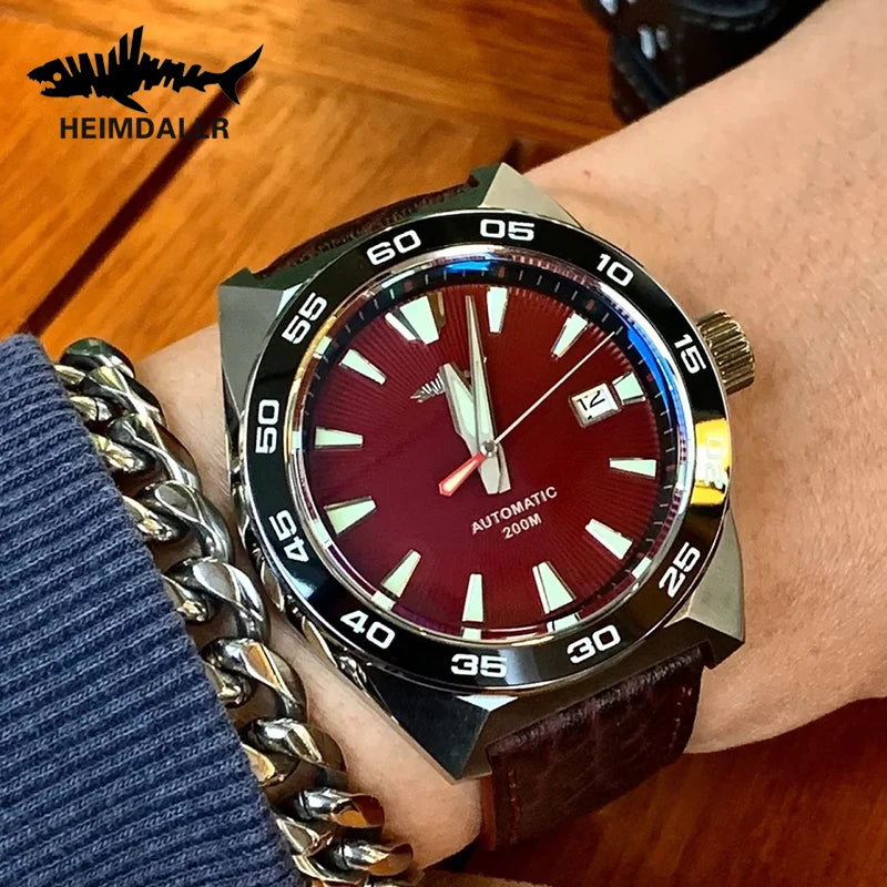 NorthChrono wristwatch featuring a red dial with silver-tone markers and hands, stainless steel case, brown leather strap, and date display at 3 o'clock. The watch is automatic, water-resistant to 200M, with a rugged design and brand name "HEIMDAHLER" visible.