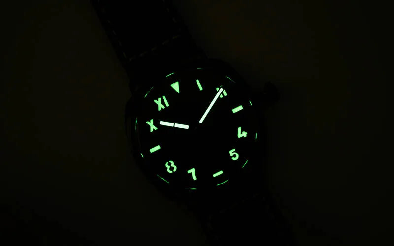 NorthChrono wristwatch featuring a black dial with glowing Roman and Arabic numerals, luminous hands, and a dark background. The design emphasizes visibility in low light, showcasing a sleek, modern aesthetic.