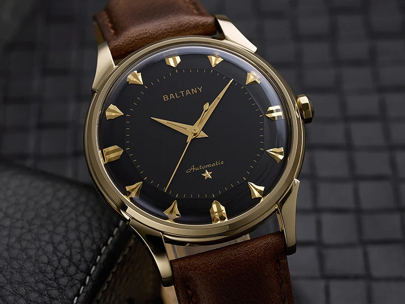 NorthChrono elegant automatic watch featuring a gold-tone case, black dial with gold hour markers, and a brown leather strap, set against a textured surface background, showcasing the "BALTANY" name prominently on the dial.