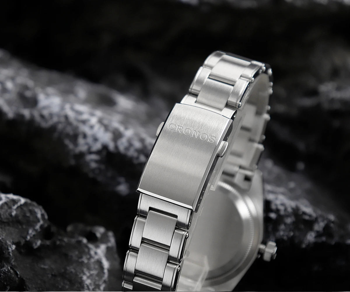 NorthChrono silver stainless steel watch with a polished finish, featuring a metal band and engraved "CRONOS" clasp, set against a textured rocky background. Close-up view highlights modern design and quality craftsmanship.