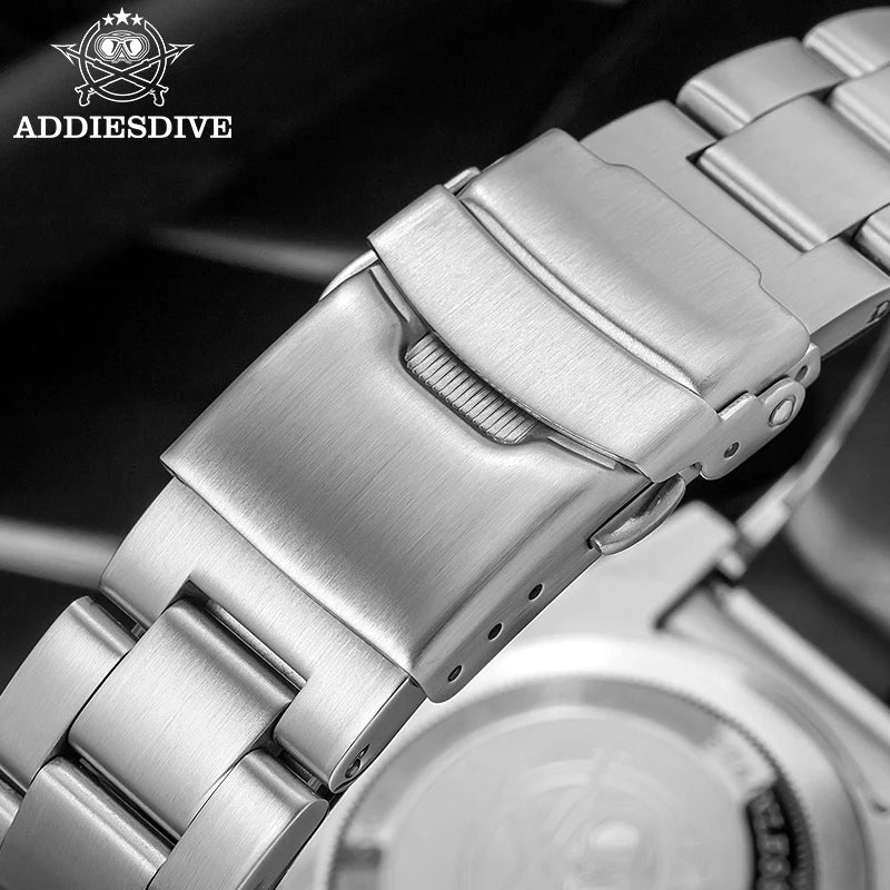 NorthChrono close-up of a polished stainless steel watch band with a deployment clasp, set against a dark background. The band features a smooth texture and prominently displays the "ADDIESDIVE" logo in the top left corner.
