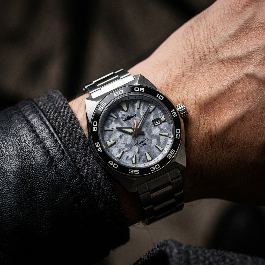 NorthChrono close-up of a modern stainless steel watch on a male wrist, featuring a textured light-colored dial with luminous markers and hands, a date display at 3 o'clock, set against a background of a leather jacket.